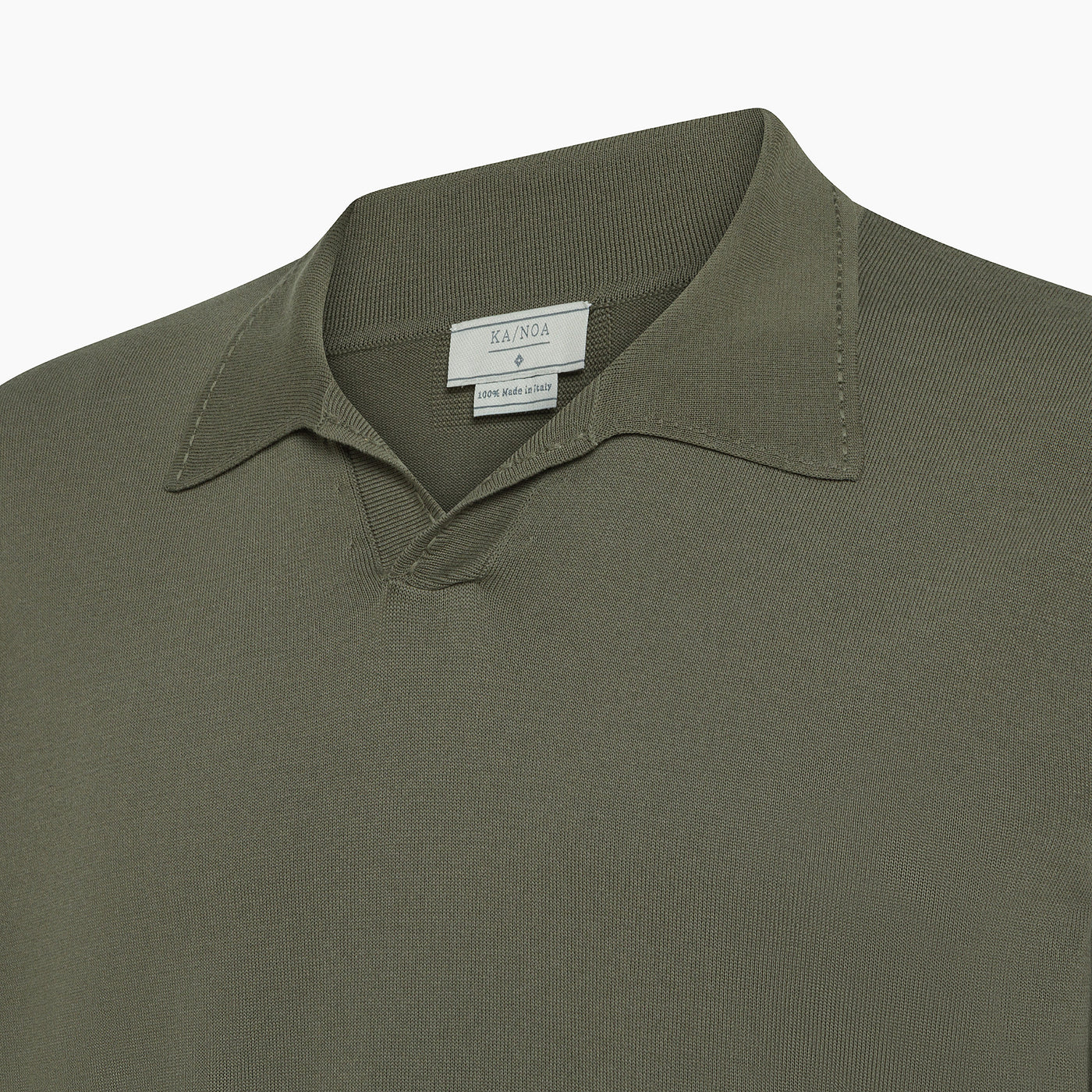Close-up of a light kaki Ailard model of the polo shirt with a classic collar and the label "KA/NOA, 100% Made in Italy."